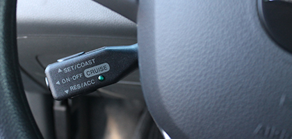 An image showing a cruise control switch through the opening in a steering wheel