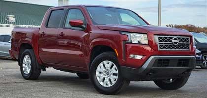 An image showing a red Nissan Frontier in a parking lot.